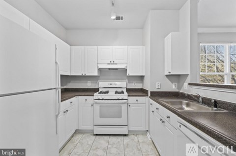 A kitchen with white cabinets and appliances.