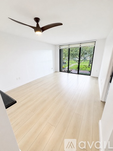 A room with a ceiling fan and a sliding glass door leading to a green outdoor area.