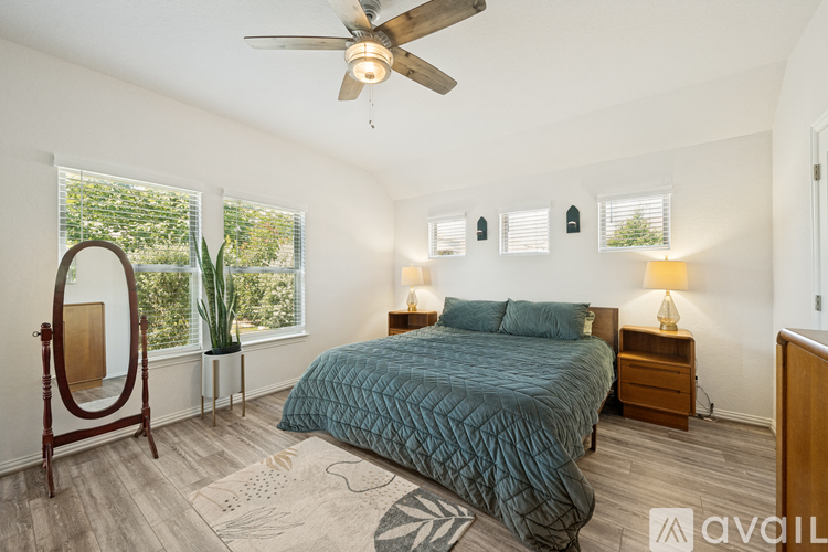 A bedroom with a bed, dresser, mirror, and ceiling fan.