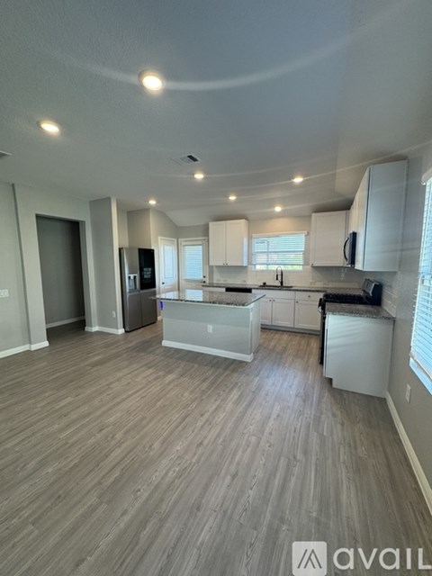 A spacious kitchen with white cabinets and a wooden floor.