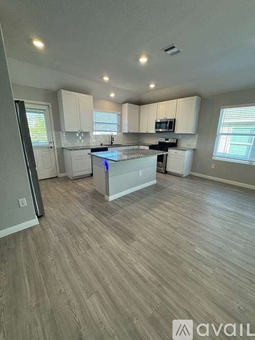 A kitchen with white cabinets and a wooden floor.