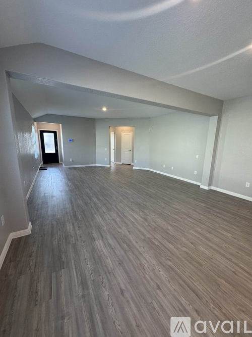 A spacious room with wooden flooring and white walls.