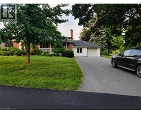 A black car is parked on a driveway leading to a house.