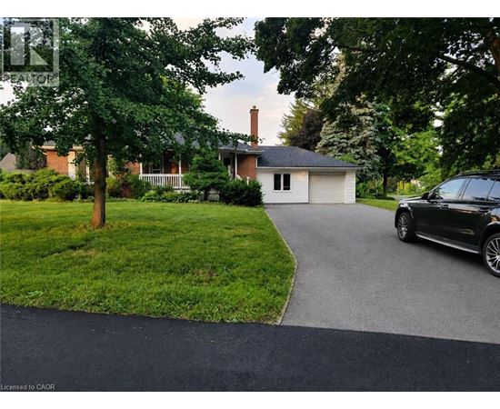 A black car is parked on a driveway leading to a house.