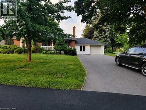 A black car is parked on a driveway leading to a house.