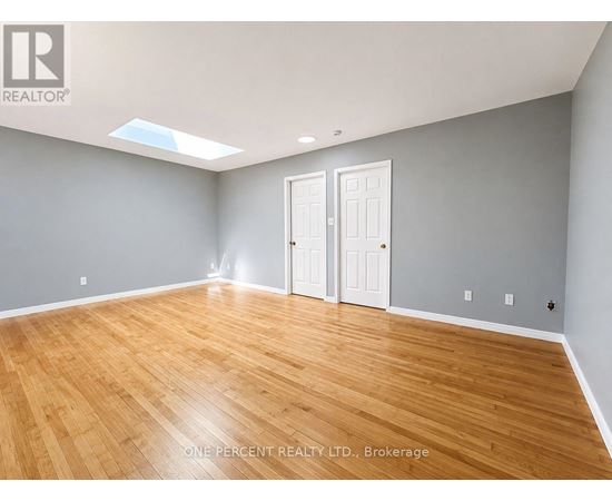 A room with wooden flooring and two white doors.