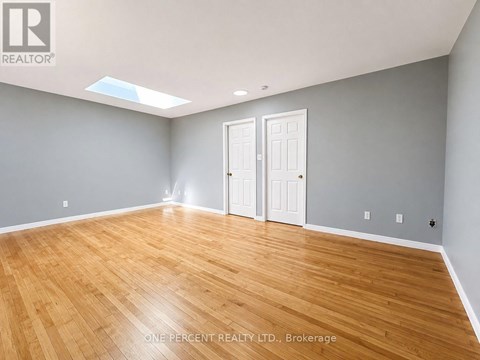 A room with wooden flooring and two white doors.