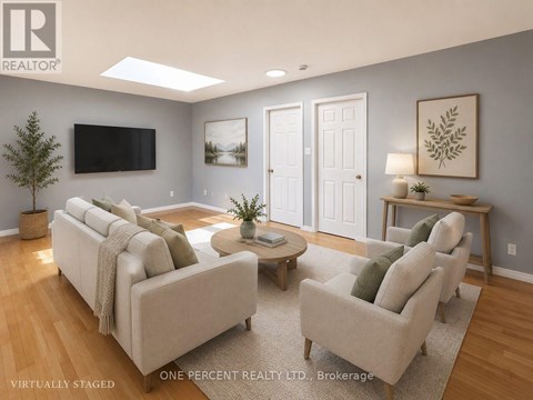 A living room with a couch, chairs, and a television.