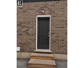 A black door with a white frame is set in a brick wall.