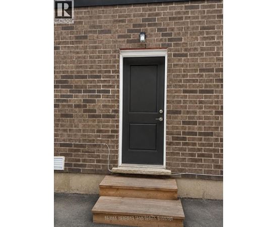 A black door with a white frame is set in a brick wall.