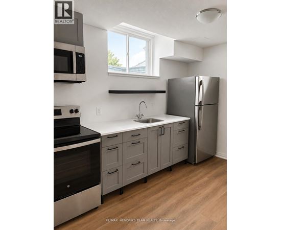 A kitchen with a refrigerator, sink, and stove.