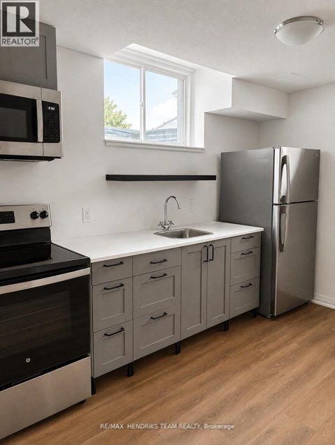 A kitchen with a refrigerator, sink, and stove.