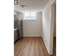 A kitchen with a refrigerator, cabinets, and a window.