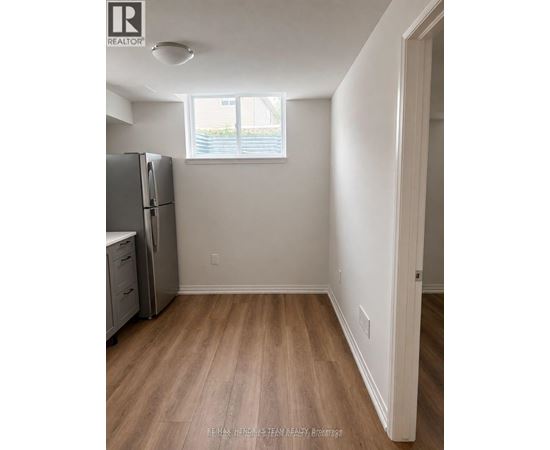 A kitchen with a refrigerator, cabinets, and a window.