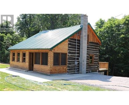 A wooden cabin with a green roof is surrounded by trees.