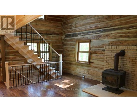 A wood stove is in a room with wooden walls.