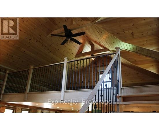 A wooden staircase with a metal railing and a ceiling fan.