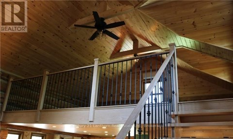 A wooden staircase with a metal railing and a ceiling fan.