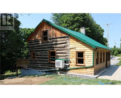 A wooden house with a green roof is for sale.