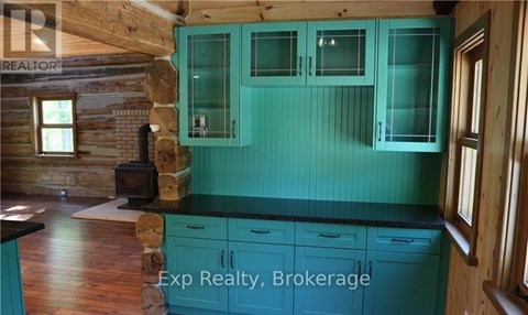 A kitchen with teal cabinets and a wood stove.
