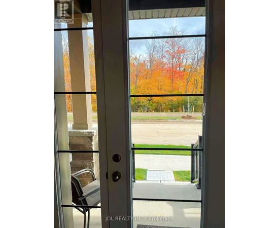 A glass door with a handle and a glass window with a view of a tree with orange leaves.