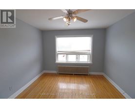 A room with a ceiling fan and a window with a view of a building outside.