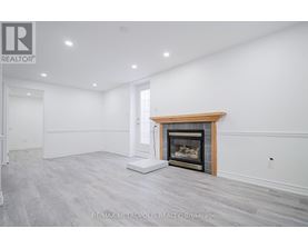 A spacious room with a fireplace and a white wall.