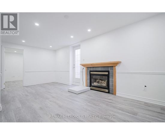 A spacious room with a fireplace and a white wall.
