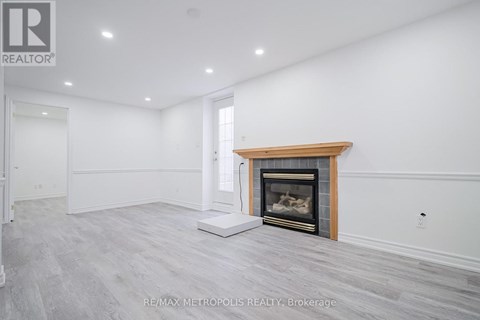 A spacious room with a fireplace and a white wall.