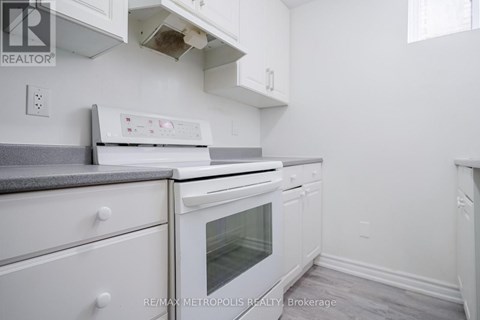 A white kitchen with a stove top oven and a microwave.