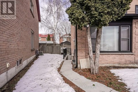 A snow-covered sidewalk leads to a brick building with a tree in front.