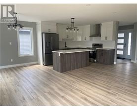 A modern kitchen with wooden floors and a central island.