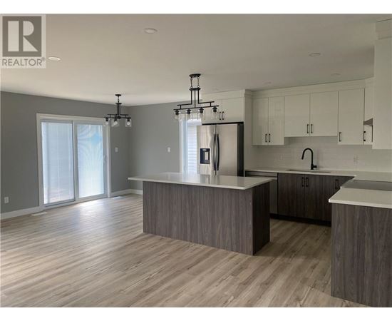 A modern kitchen with a large island and a refrigerator.