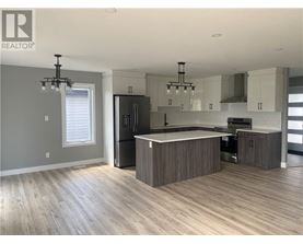 A modern kitchen with wooden floors and a central island.