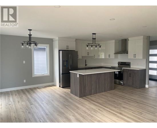 A modern kitchen with wooden floors and a central island.