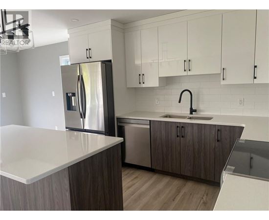 A modern kitchen with a stainless steel refrigerator and wooden cabinets.