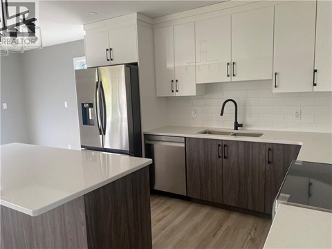 A modern kitchen with a stainless steel refrigerator and wooden cabinets.