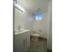 A bathroom with a toilet, sink, and cabinet.
