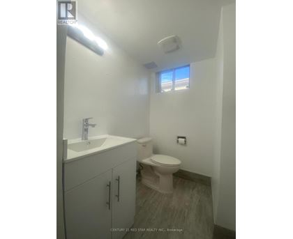A bathroom with a toilet, sink, and cabinet.