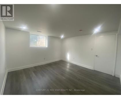 A room with wooden flooring and white walls, with a window and a door.