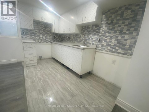A kitchen with a checkered backsplash and wooden flooring.