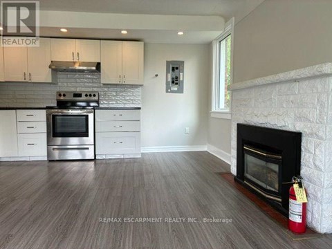 A modern kitchen with a fireplace and a brokerage logo.
