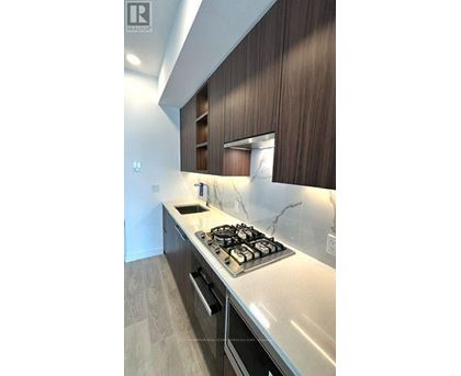 A modern kitchen with a stove top oven and wooden cabinets.