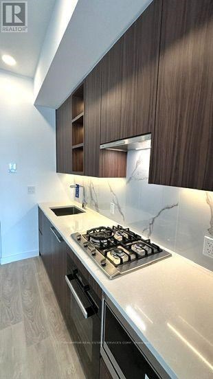 A modern kitchen with a stove top oven and wooden cabinets.