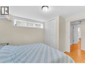 A bedroom with a bed and a window with blinds.