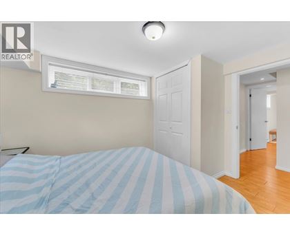 A bedroom with a bed and a window with blinds.