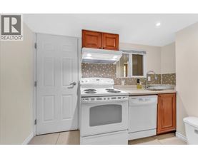 A white stove and oven in a kitchen with a white door and brown cabinets.