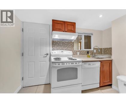 A white stove and oven in a kitchen with a white door and brown cabinets.