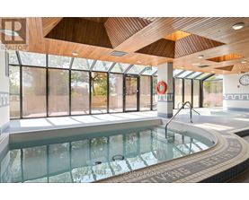 A large indoor swimming pool with a wooden ceiling and a glass wall.