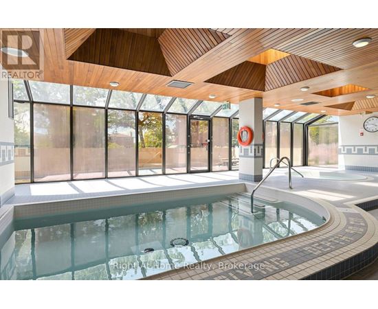 A large indoor swimming pool with a wooden ceiling and a glass wall.